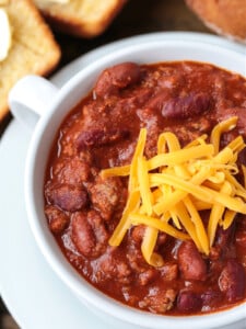 close up of ground beef chili in bowl with cheese