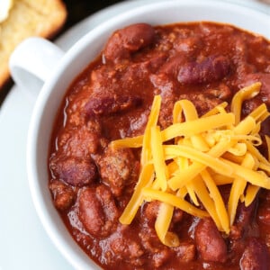 close up of ground beef chili in bowl with cheese