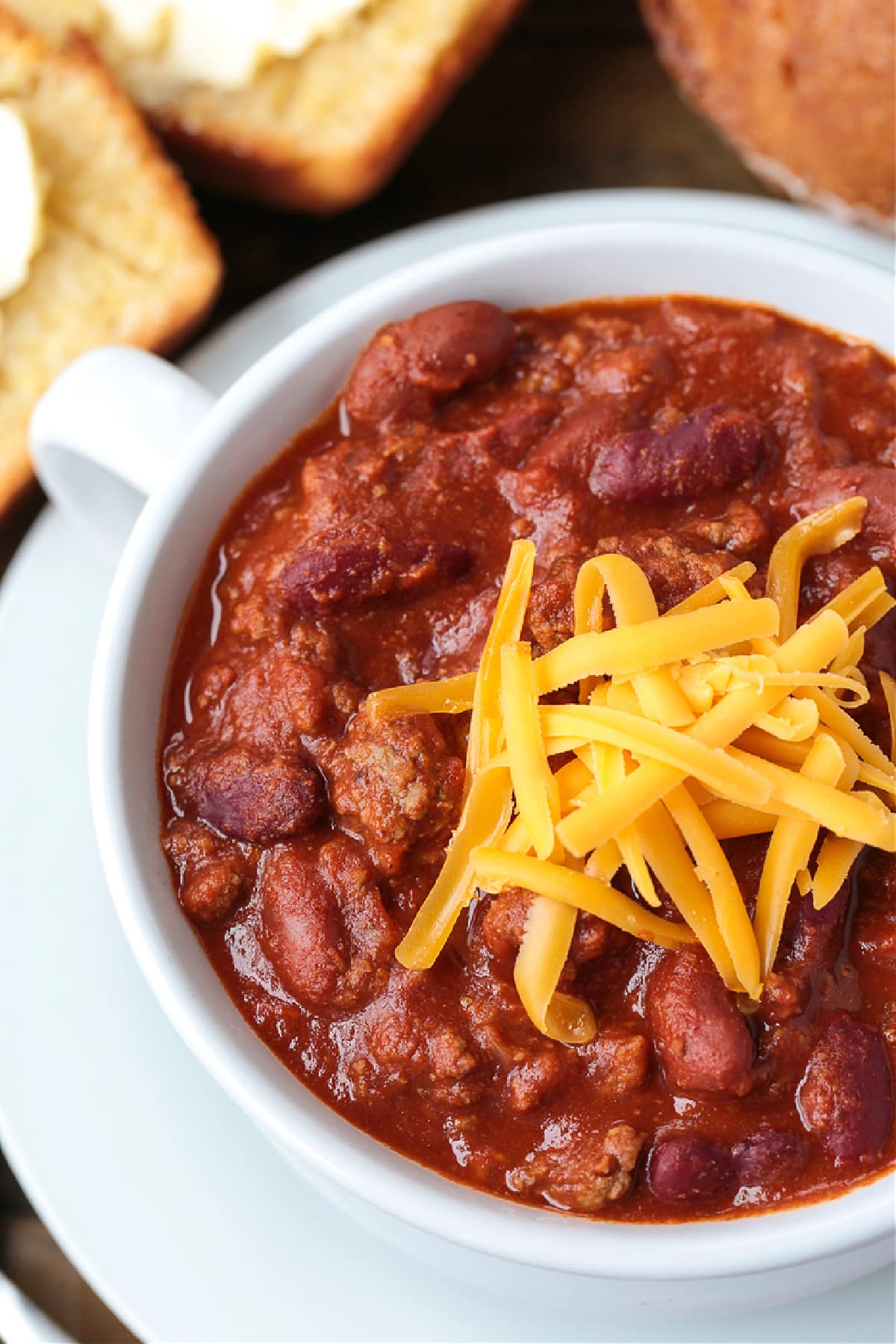 close up of ground beef chili in bowl with cheese