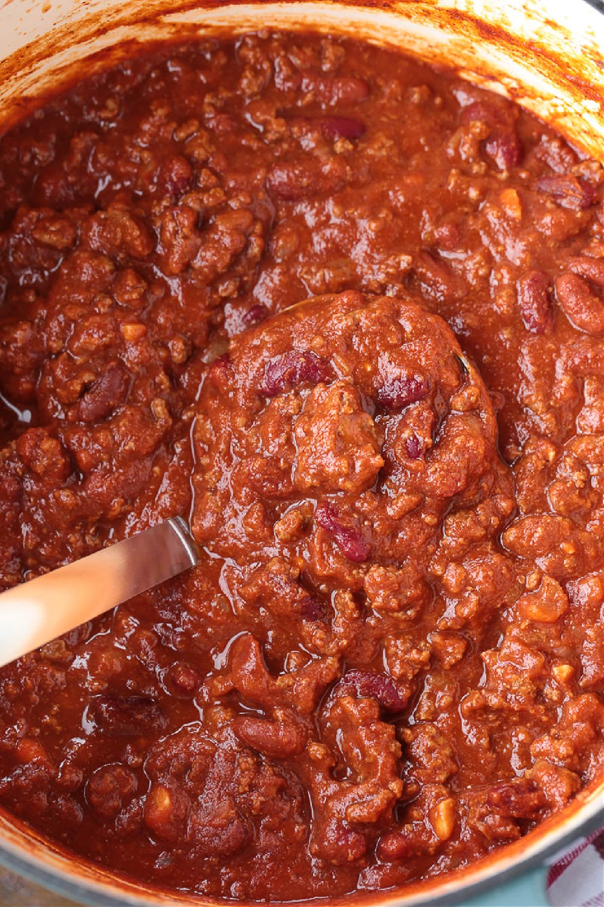 Our Ground Beef Chili recipe is loved by all! Not too spicy with big, bold flavors. Make a big batch for the week, leftovers are even better! pot of chili with ladle