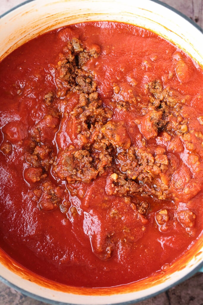 Our Ground Beef Chili recipe is loved by all! Not too spicy with big, bold flavors. Make a big batch for the week, leftovers are even better! ground beef in pot with tomato sauce and seasonings