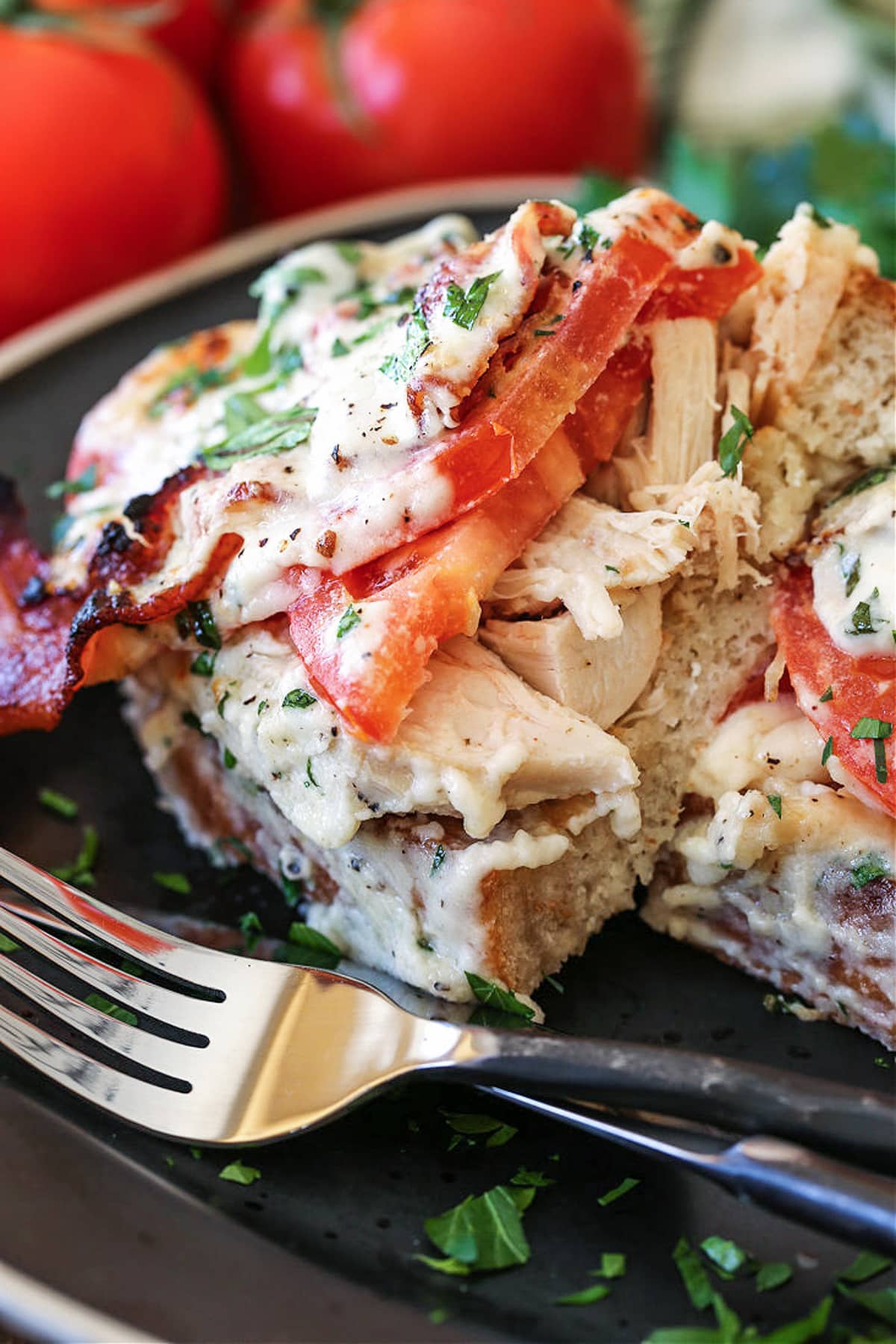 A Kentucky Hot Brown Sandwich is a delicious way to use leftover turkey. Baked with slices of tomato and bacon smothered in a cheesy sauce! kentucky hot brown sliced on a plate with fork
