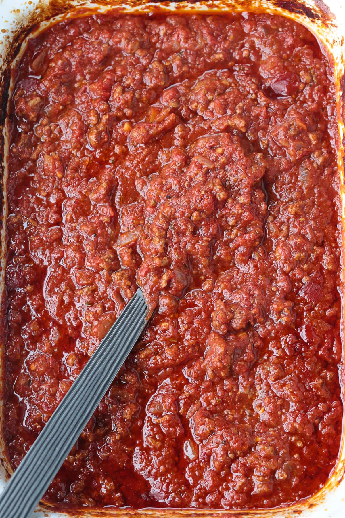 cooked spaghetti sauce with ground beef in a slow cooker with a spoon