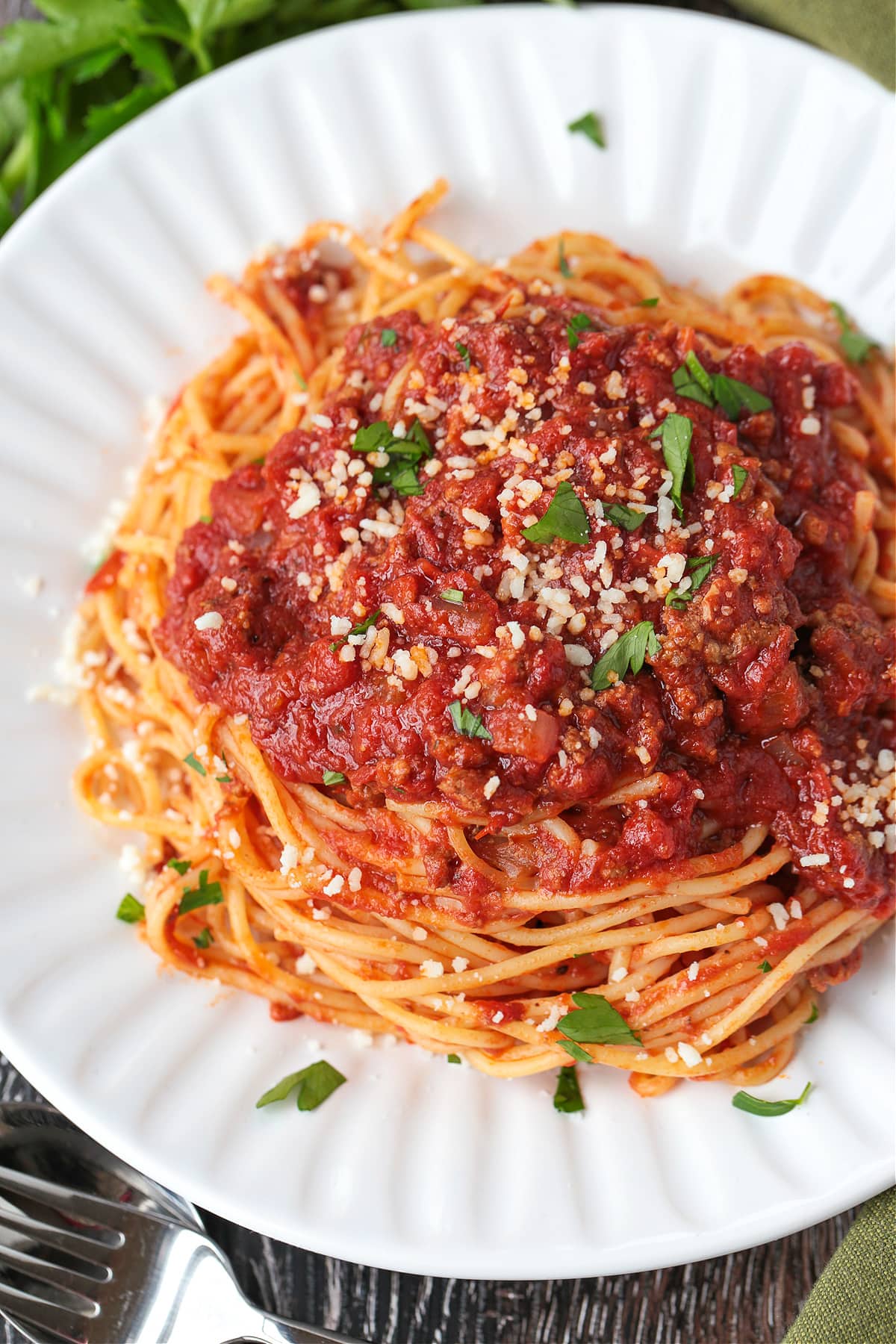 spaghetti sauce with ground beef on top of spaghetti on white plate