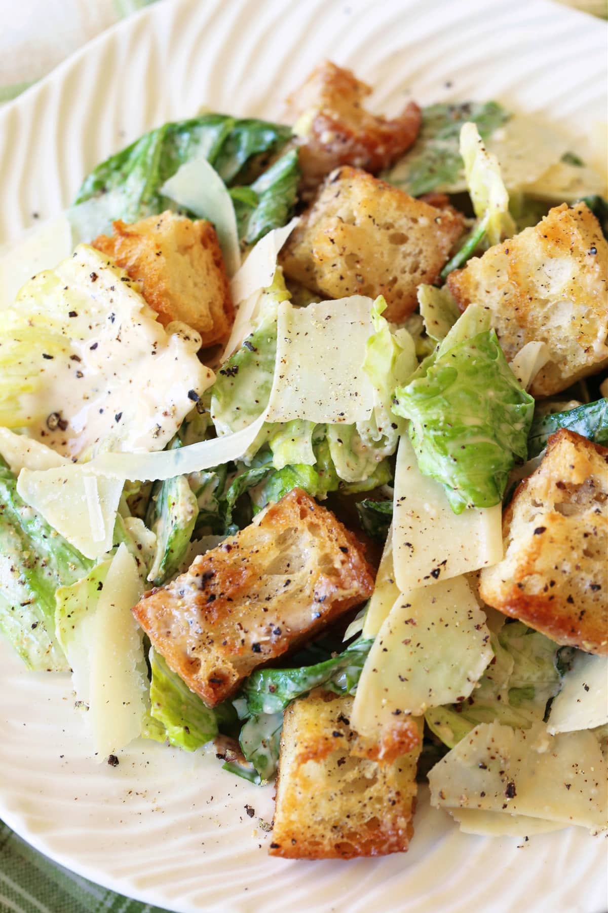 The BEST Creamy Caesar Salad Dressing ever. A secret ingredient makes our dressing stand out from the rest, you'll never need another recipe. caesar salad on white plate with croutons