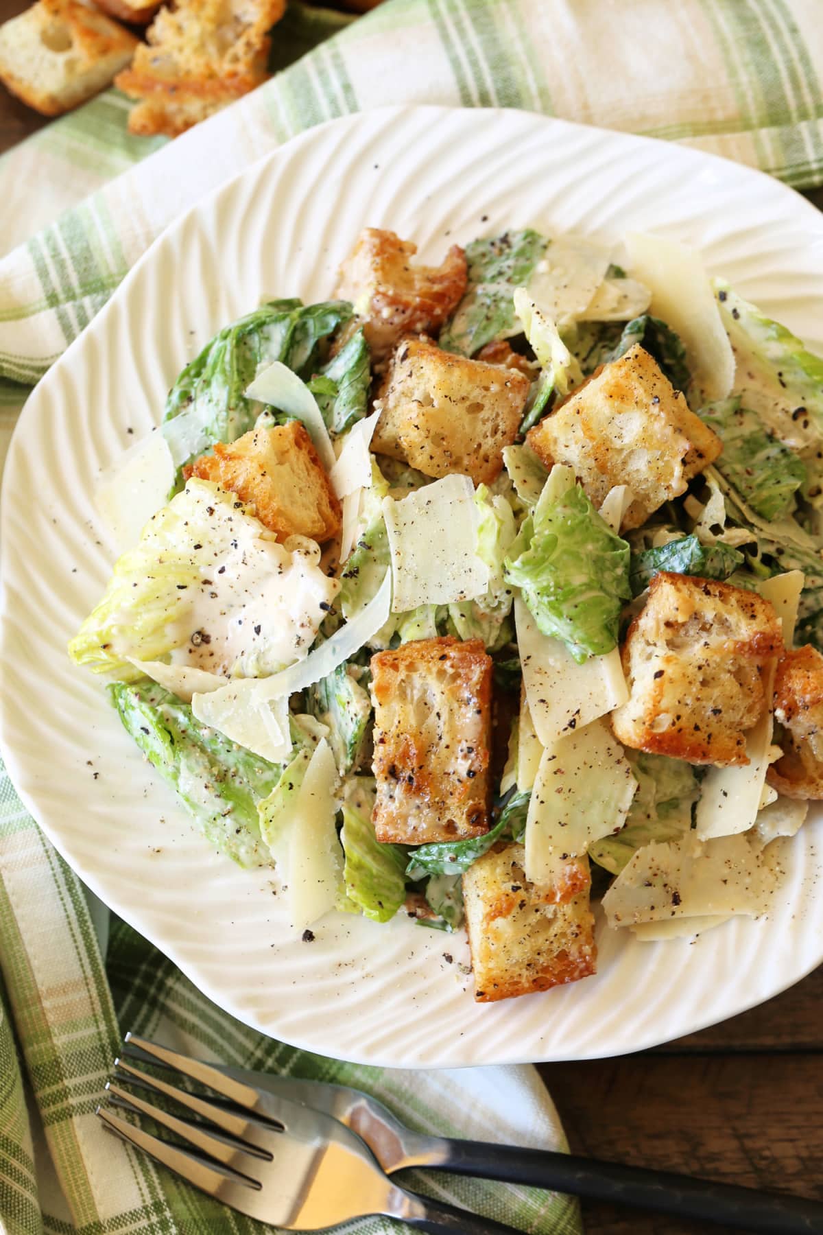 The BEST Creamy Caesar Salad Dressing ever. A secret ingredient makes our dressing stand out from the rest, you'll never need another recipe. caesar salad on white plate with napkin