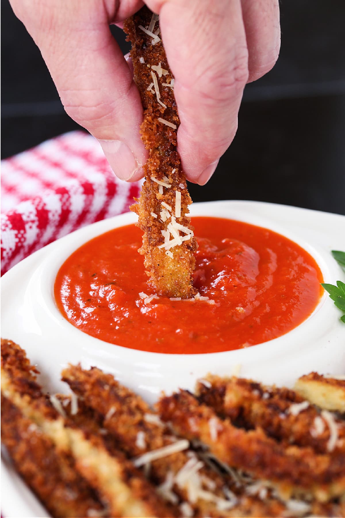 Crispy Eggplant Fries are so addicting! Breaded, lightly fried eggplant strips topped with parmesan cheese and dipped into marinara sauce. eggplant fry dipping into marinara sauce