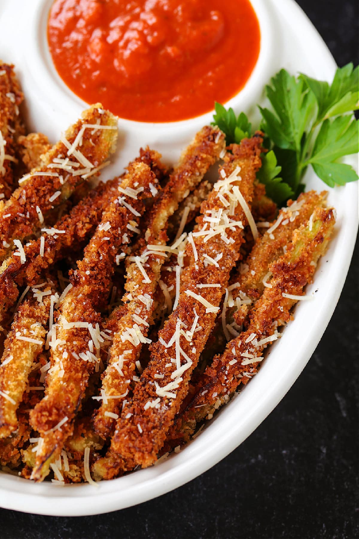 Crispy Eggplant Fries are so addicting! Breaded, lightly fried eggplant strips topped with parmesan cheese and dipped into marinara sauce. eggplant fries in a bowl with parmesan cheese and sauce