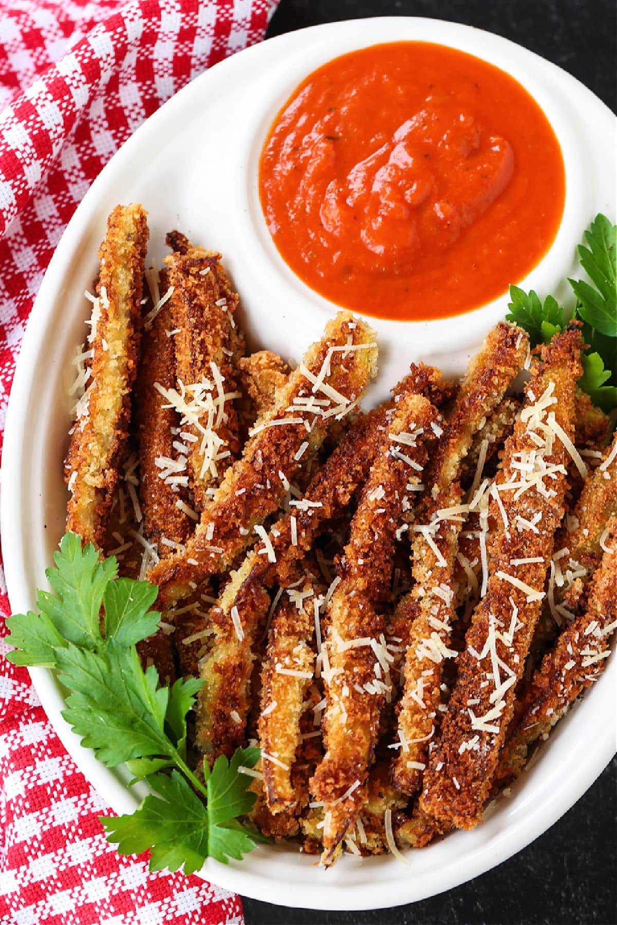Crispy Eggplant Fries are so addicting! Breaded, lightly fried eggplant strips topped with parmesan cheese and dipped into marinara sauce. eggplant fries on a platter with marinara sauce