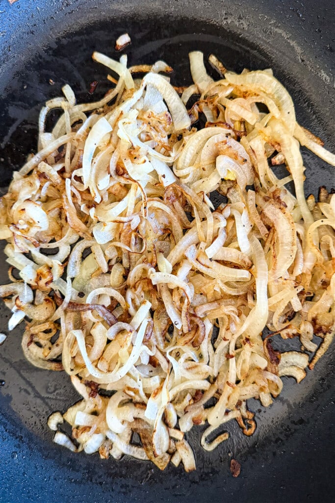 Our French Dip Sliders have a secret sauce that sets them apart from the rest. Beefy, cheesy comfort food perfect for parties and game days! caramelized onions in skillet