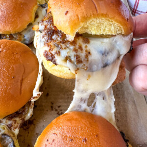 A cheese and roast beef slider being pulled from a sheet pan