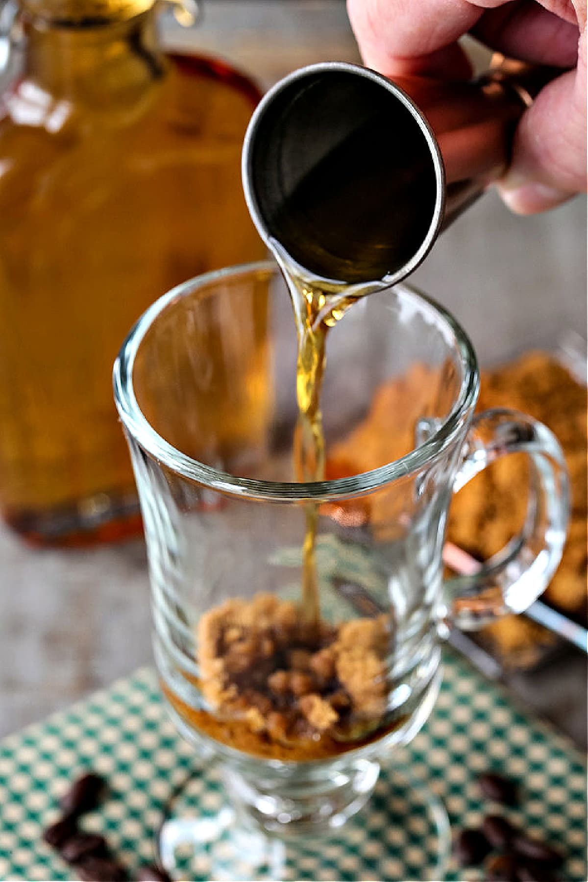 This classic Irish Coffee recipe can be served for an after dinner drink or for brunch. Slightly sweetened coffee with splash of whiskey! whiskey being poured into glass mug with brown sugar