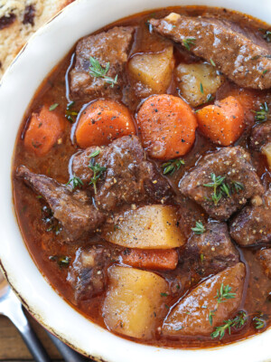 beef stew with potatoes and carrots in bowl with spoon on side