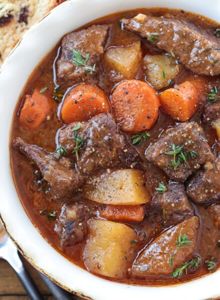 beef stew with potatoes and carrots in bowl with spoon on side