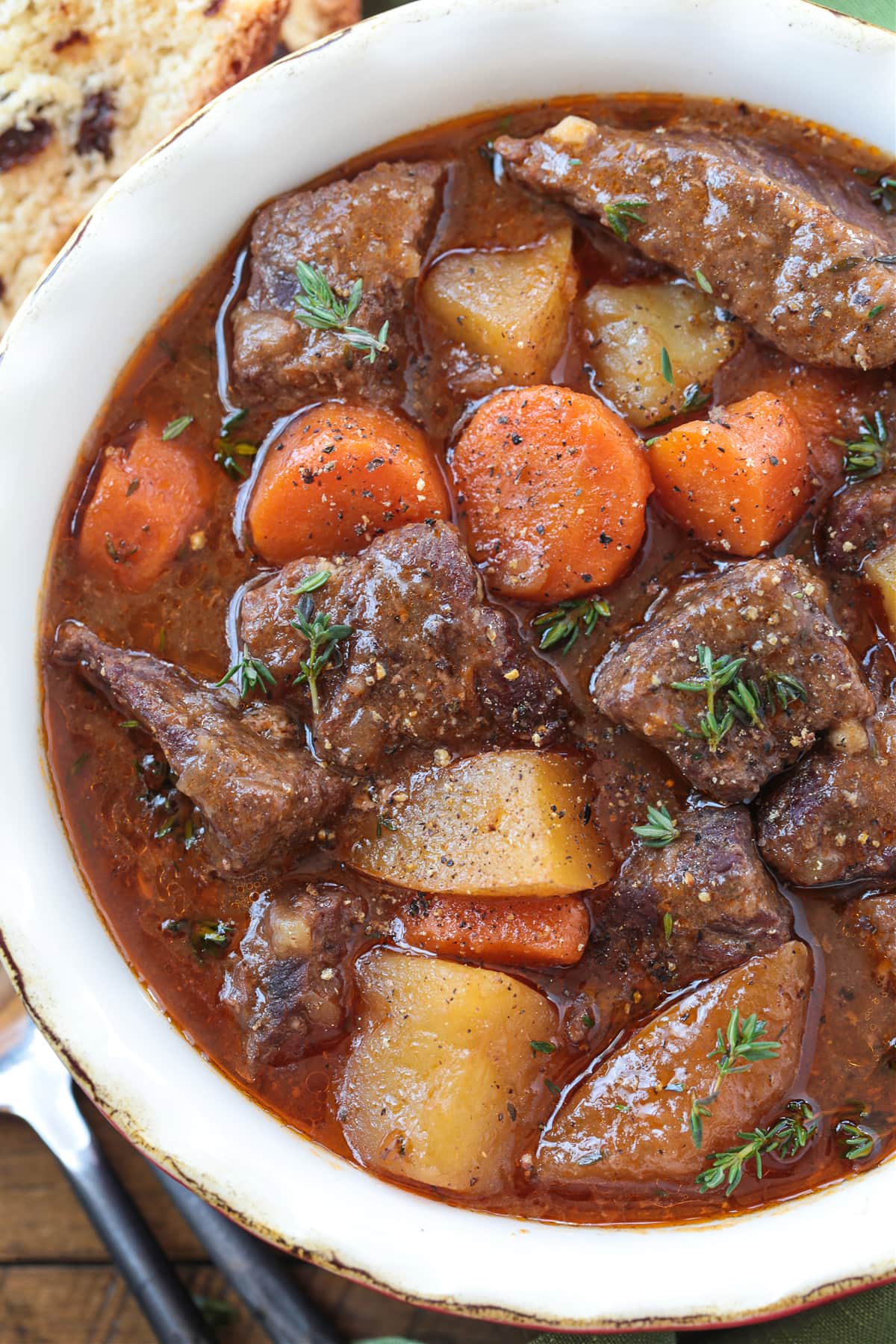 beef stew with potatoes and carrots in bowl with spoon on side