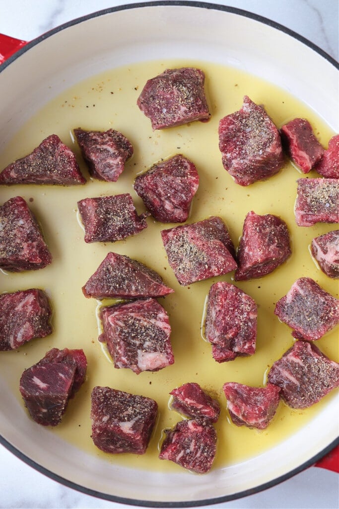 This Irish Stew Recipe is packed with tender beef and vegetables, simmered in a beer and wine gravy. A comfort food dinner all in one pot! raw beef cubes in pot with oil