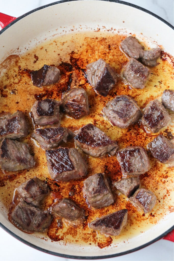 Seared beef cubes in pot with oil.