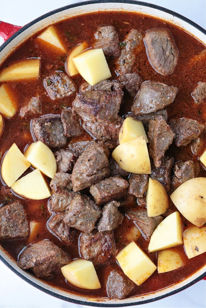 This Irish Stew Recipe is packed with tender beef and vegetables, simmered in a beer and wine gravy. A comfort food dinner all in one pot! beef tips and potatoes in pot for making Irish stew