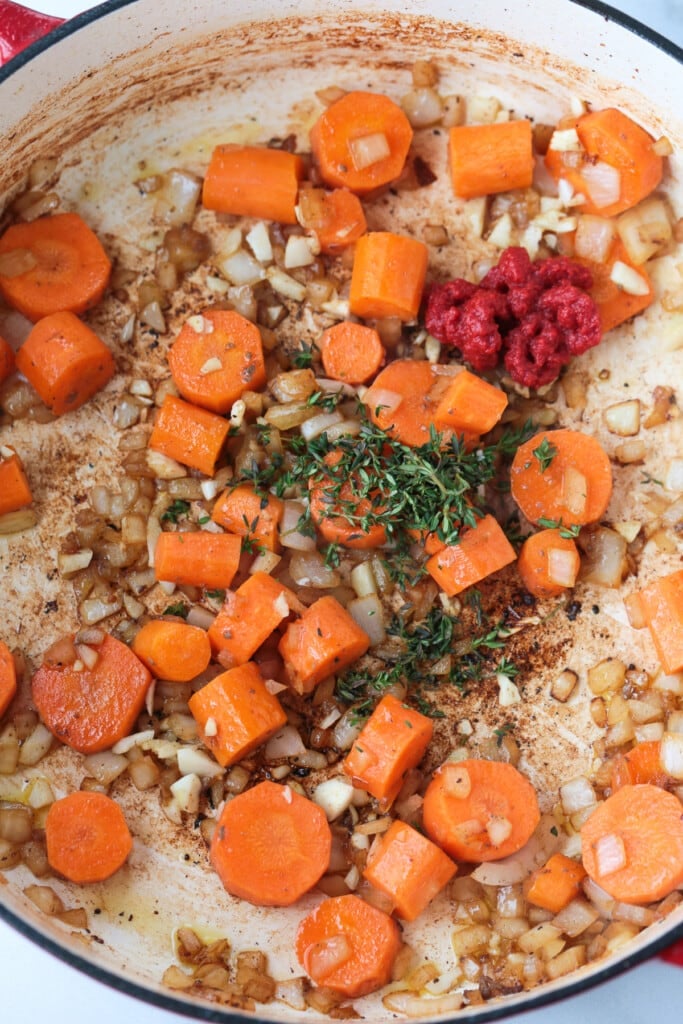 This Irish Stew Recipe is packed with tender beef and vegetables, simmered in a beer and wine gravy. A comfort food dinner all in one pot! onions, carrots fresh thyme and tomato paste in pot