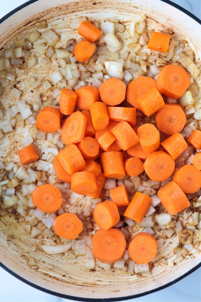 This Irish Stew Recipe is packed with tender beef and vegetables, simmered in a beer and wine gravy. A comfort food dinner all in one pot! Onions and carrots in pot for making stew