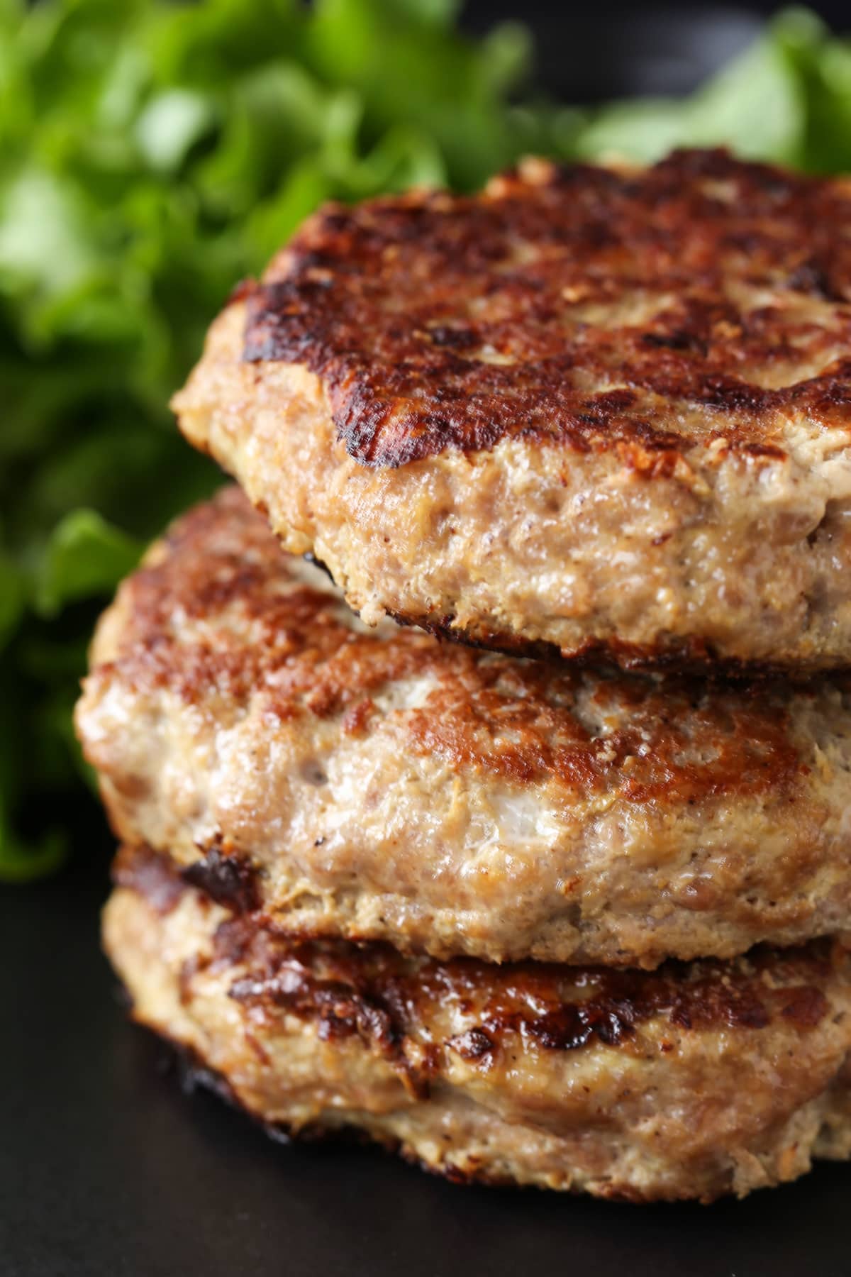 homemade turkey burgers patties stacked with lettuce in background