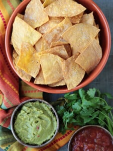 tortilla chips in large bowl with salsa and guacamole