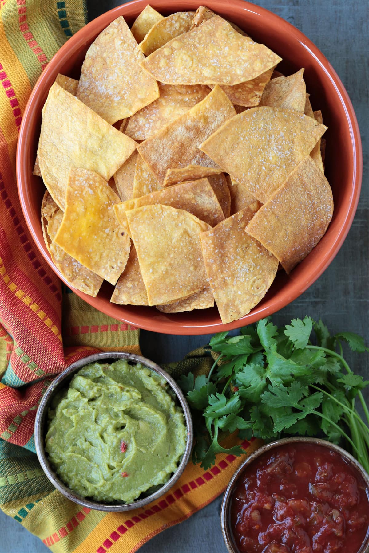 These Air Fryer Tortilla Chips are super crispy and so addicting! Dip them in salsa, serve them with soups or make a platter of nachos! tortilla chips in large bowl with salsa and guacamole