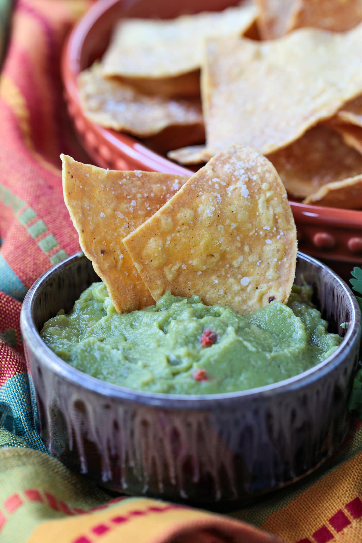 These Air Fryer Tortilla Chips are super crispy and so addicting! Dip them in salsa, serve them with soups or make a platter of nachos! tortilla chips dipped into guacamole