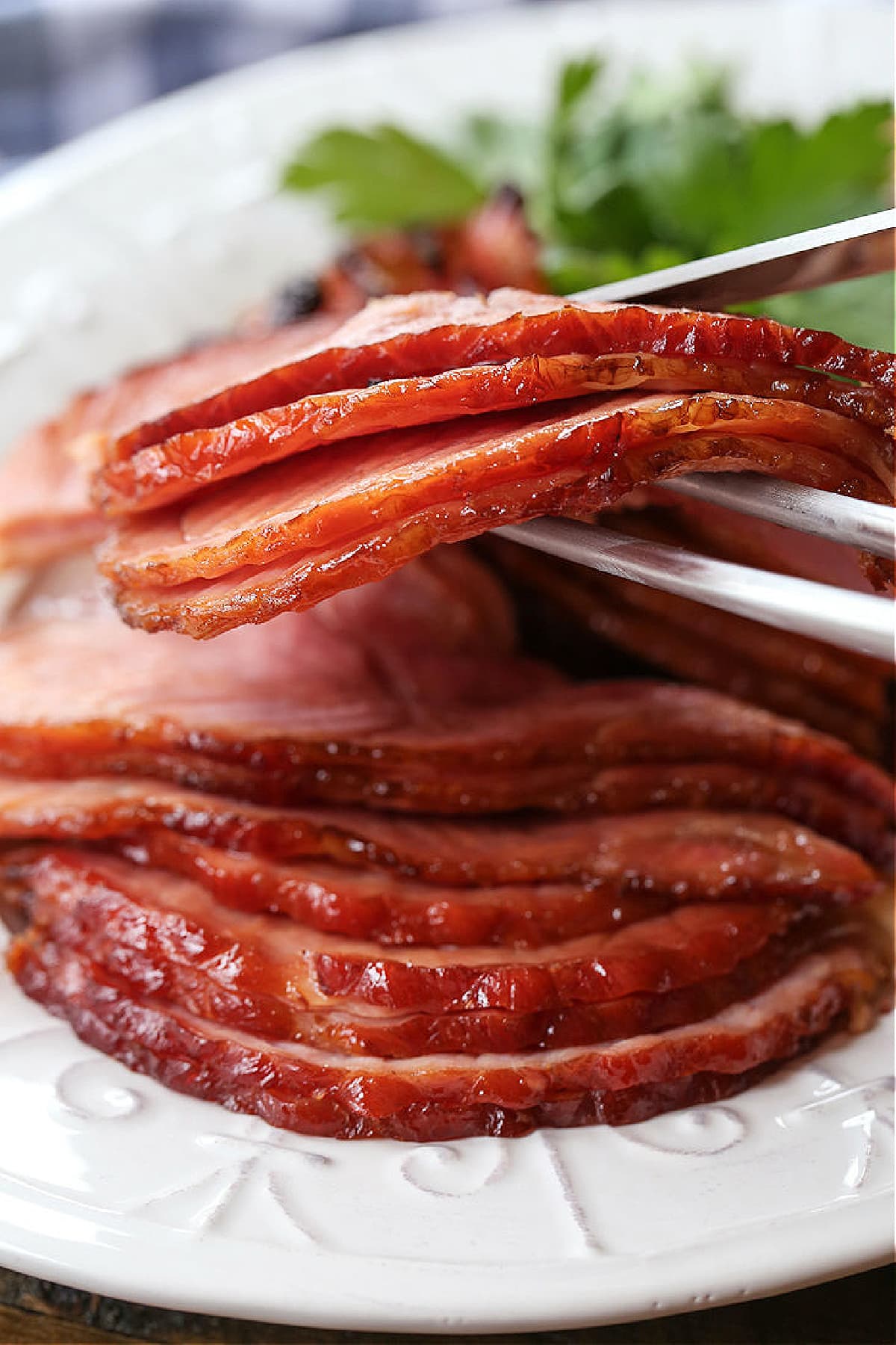 Bourbon Glazed Ham is a holiday favorite! A sweet caramelized glaze paired with the smoky taste of bourbon baked into layers of tender ham. slices of ham on serving platter with serving forks
