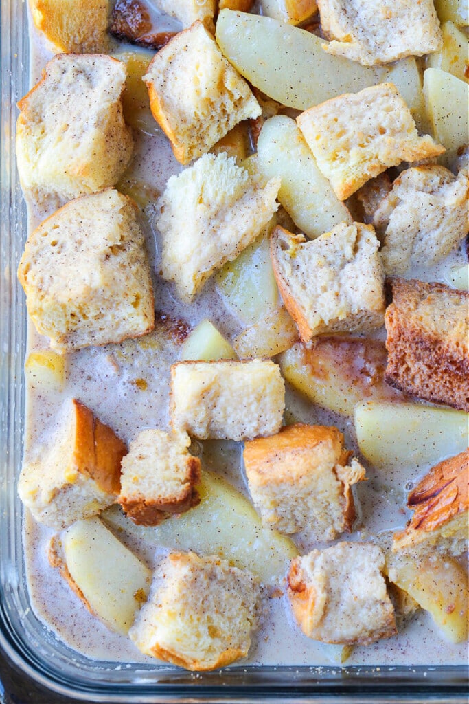 Cozy Apple Bread Pudding is one of our favorite fall desserts! Sweet, brioche bread soaked in a rich custard layered with buttery apples sliced apples with bread cubes and custard in dish