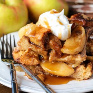 slice of apple bread pudding on plate with whipped cream
