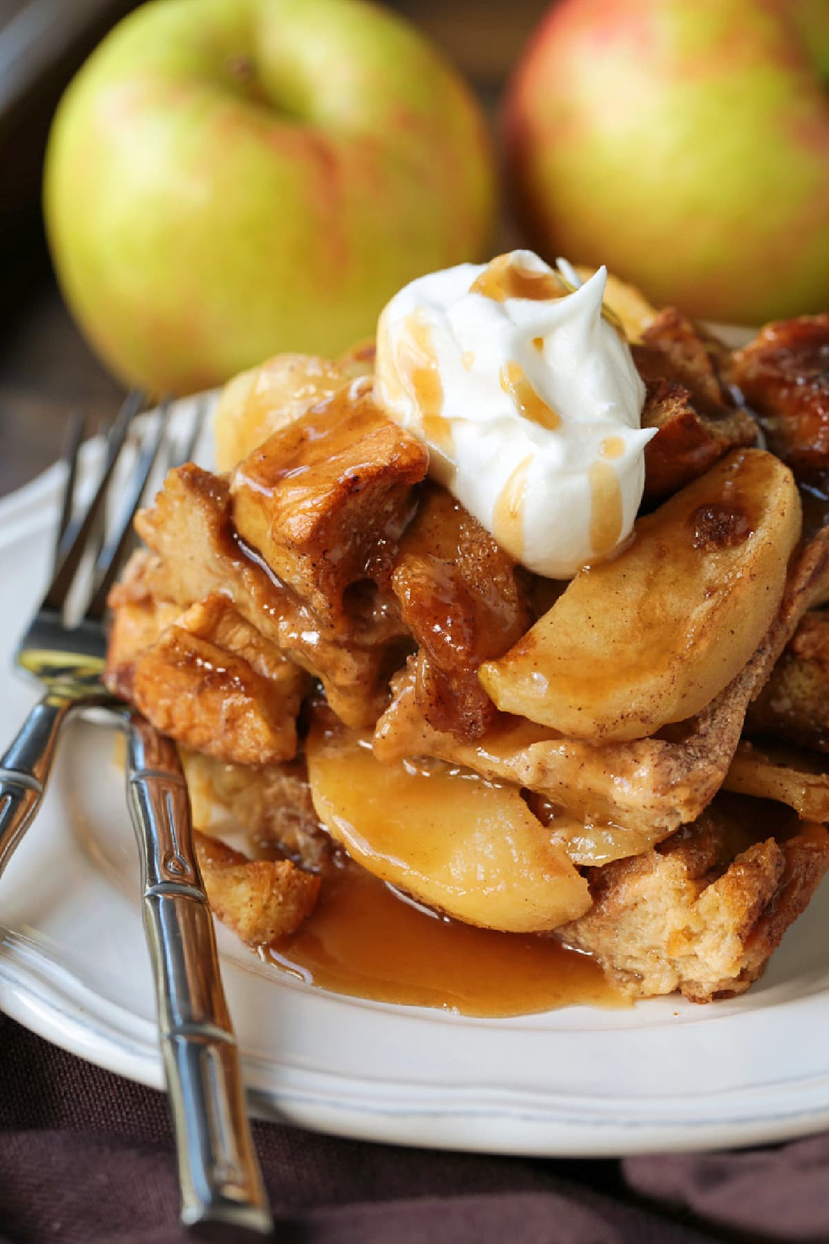 Cozy Apple Bread Pudding is one of our favorite fall desserts! Sweet, brioche bread soaked in a rich custard layered with buttery apples! slice of apple bread pudding on plate with whipped cream