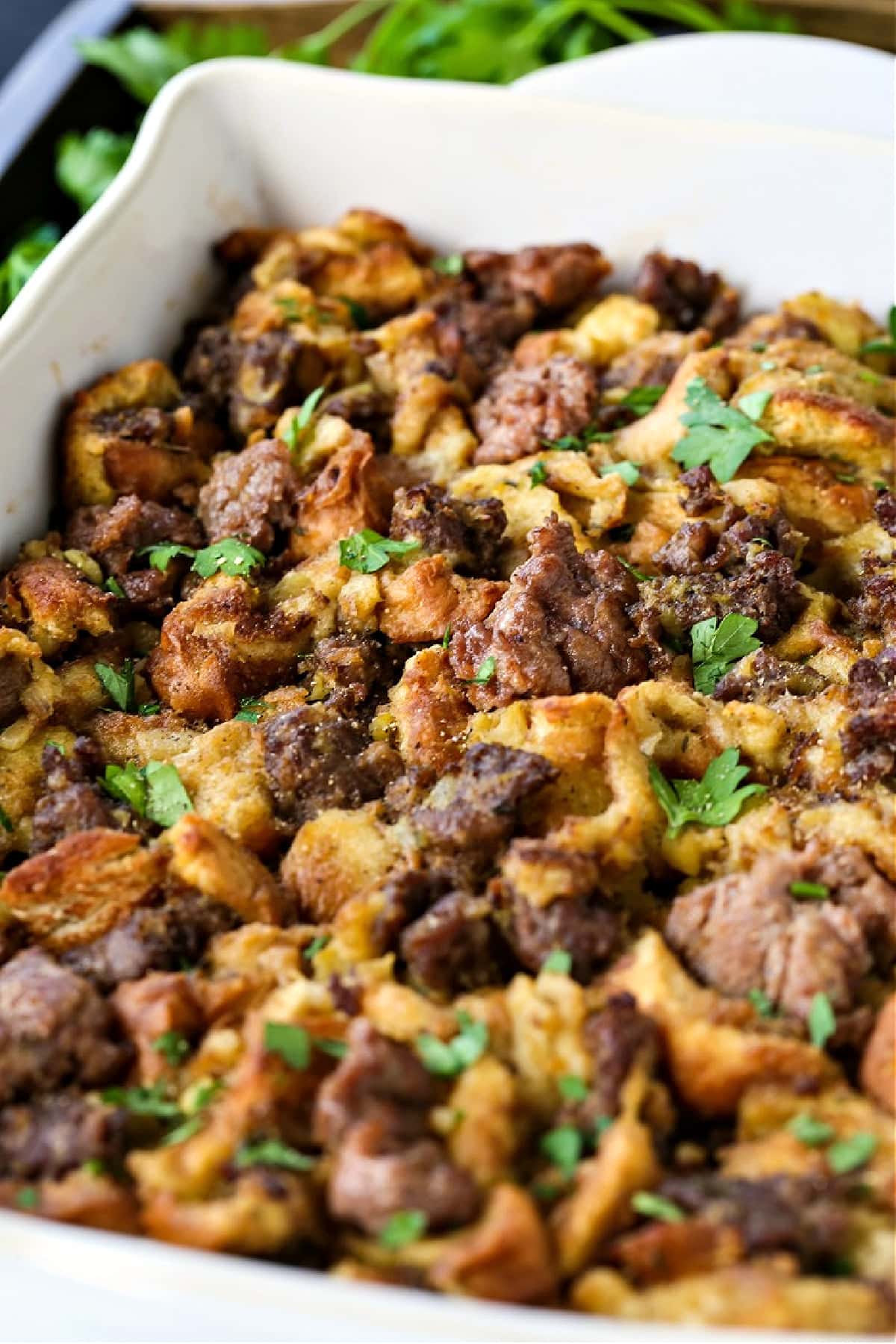 Our Sausage Stuffing Recipe is a favorite at Thanksgiving. Tons of sausage, sweet apples and buttery, toasted bread. We crave it all year! sausage stuffing in white casserole dish