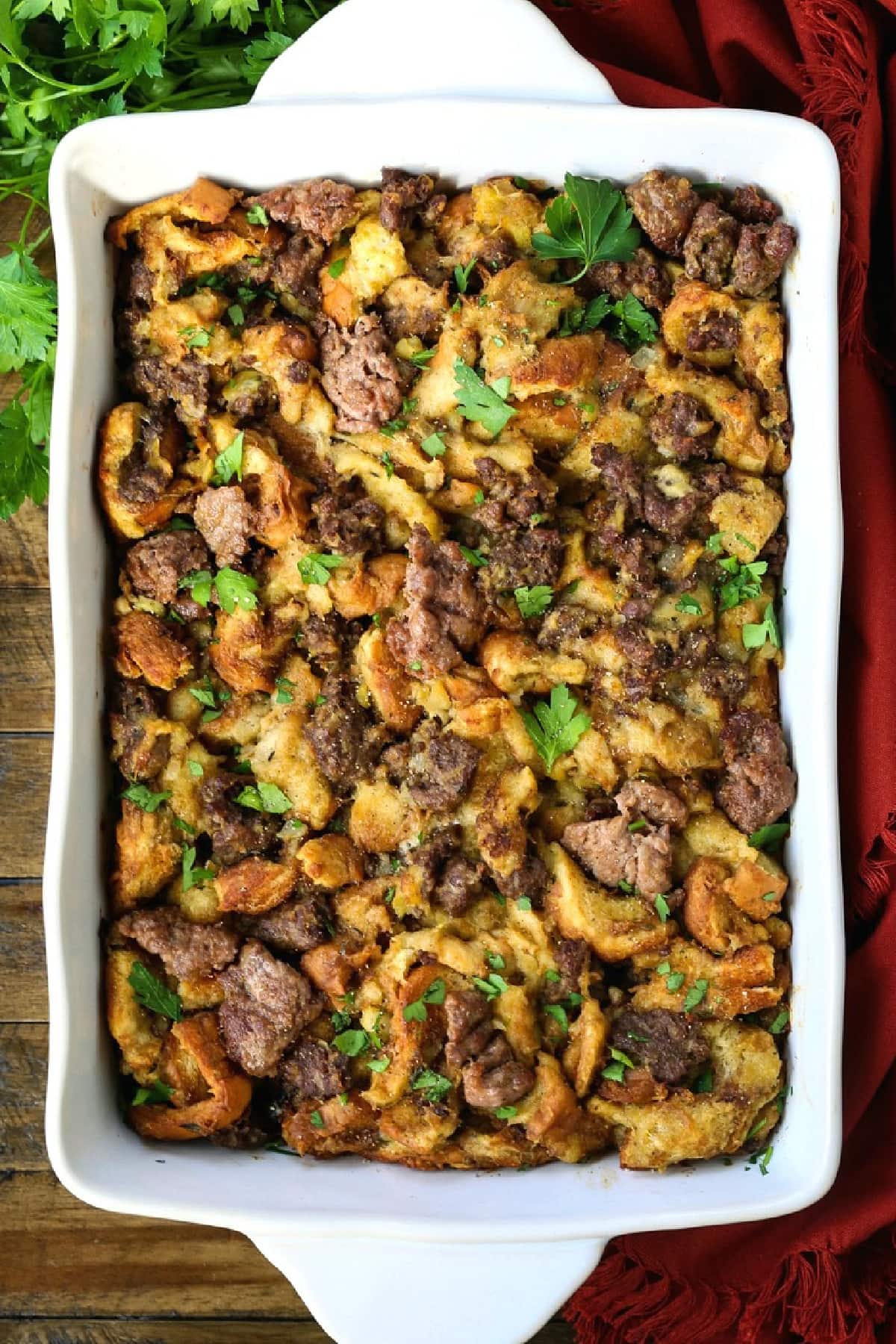 Our Sausage Stuffing Recipe is a favorite at Thanksgiving. Tons of sausage, sweet apples and buttery, toasted bread. We crave it all year! sausage stuffing in casserole dish with napkin