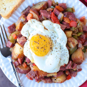 fried egg on top of corned beef hash with toast on the side