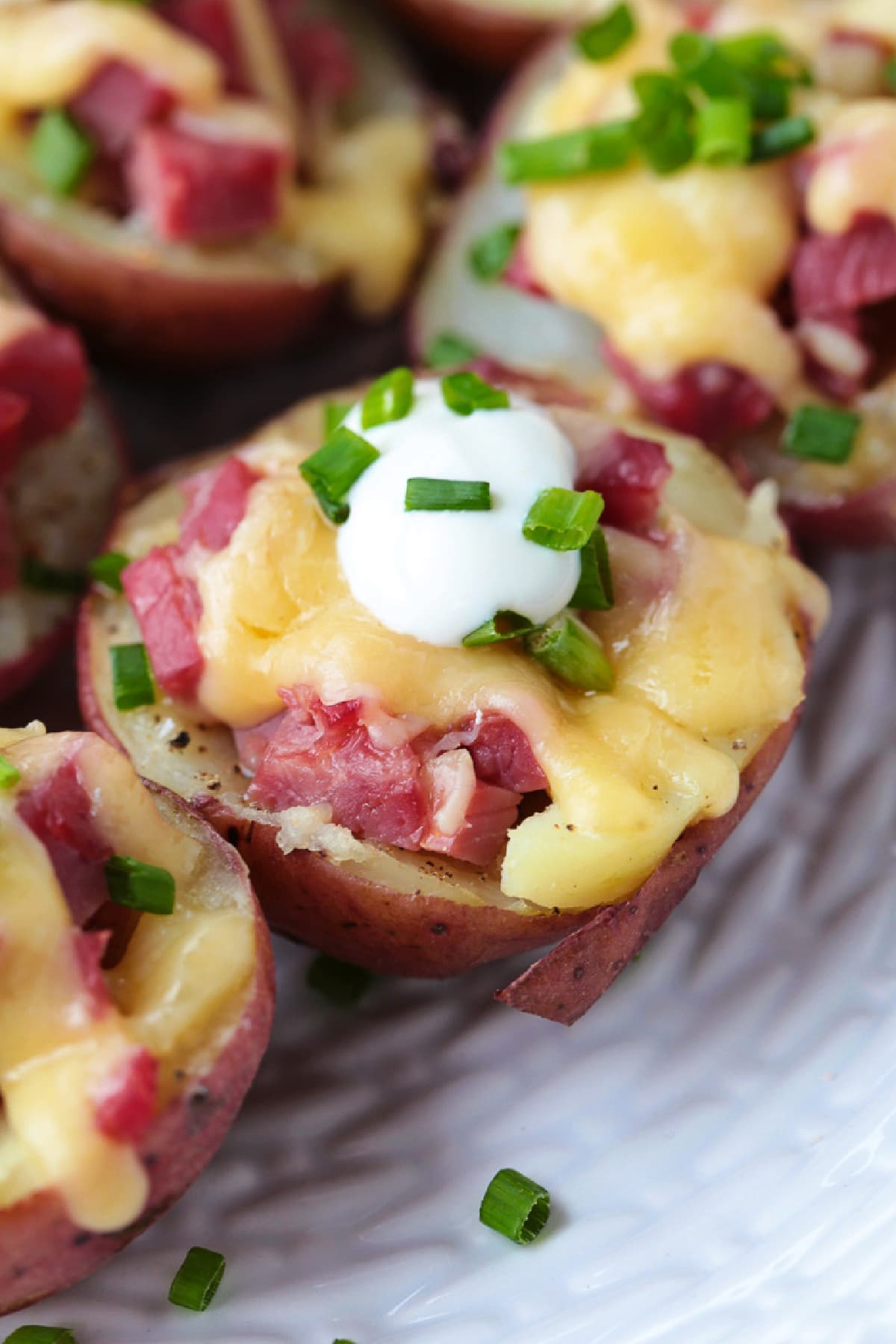 Corned Beef Stuffed Potatoes are a tasty way to use leftover corned beef! Tender baby potatoes stuffed with corned beef and cheddar cheese! mini red potatoes stuffed with corned beef and cheese topped with sour cream