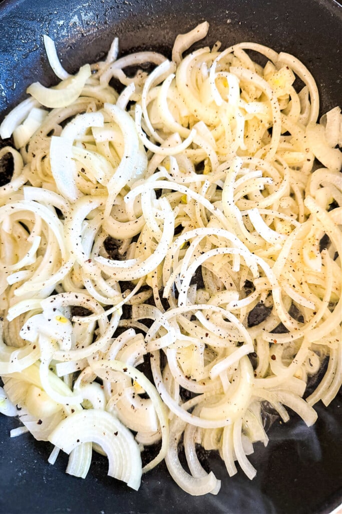 Our French Dip Sliders have a secret sauce that sets them apart from the rest. Beefy, cheesy comfort food perfect for parties and game days! sliced onions in a skillet