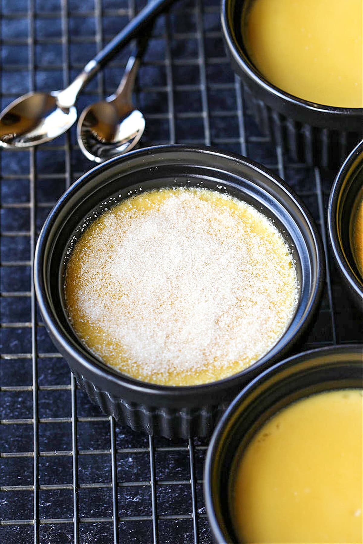 sugar sprinkled over baked custard with spoons on the side