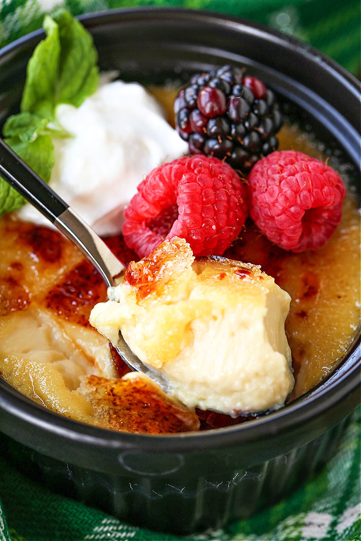 spoonful of creme brulee with berries and whipped cream