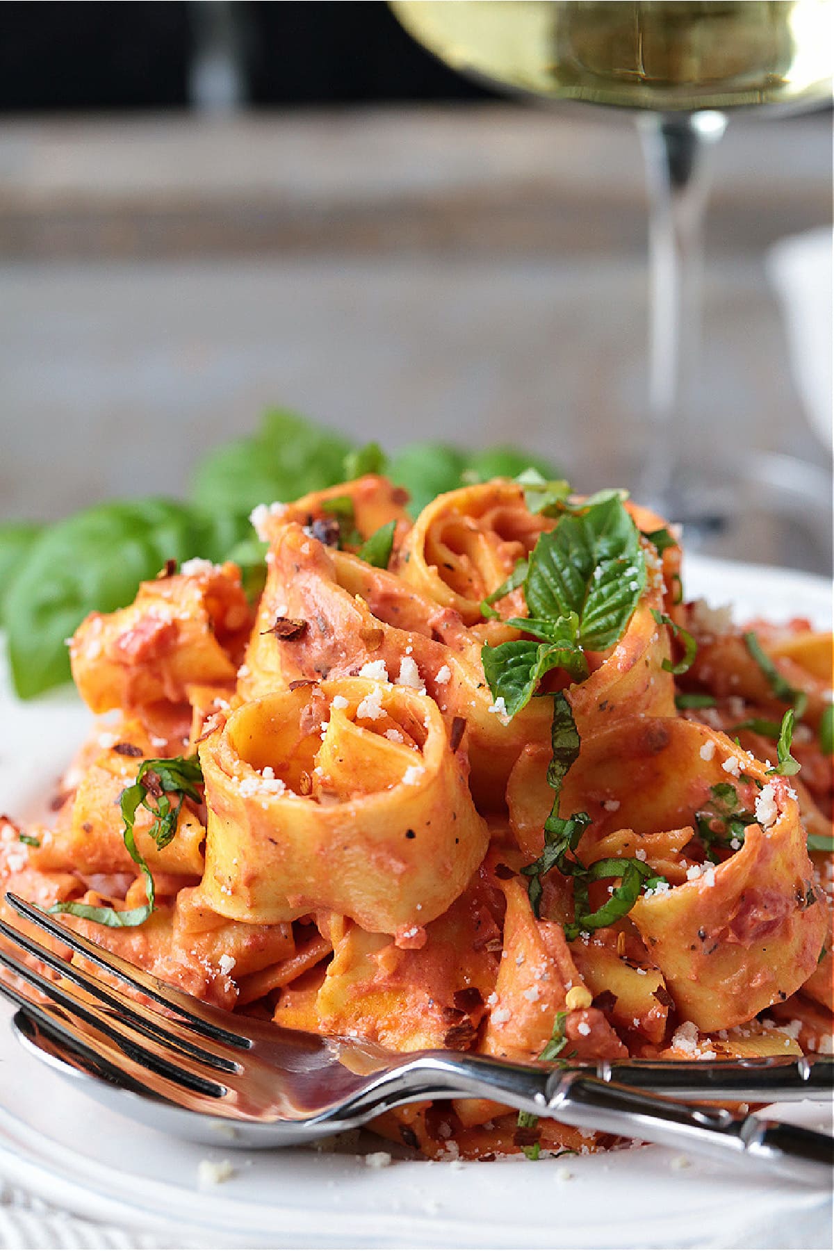 Pappardelle with Champagne Cream Sauce is perfect for the holidays! Pappardelle pasta tossed in a tomato cream sauce with real champagne! pappardelle pasta in champagne cream sauce on white plate with fork