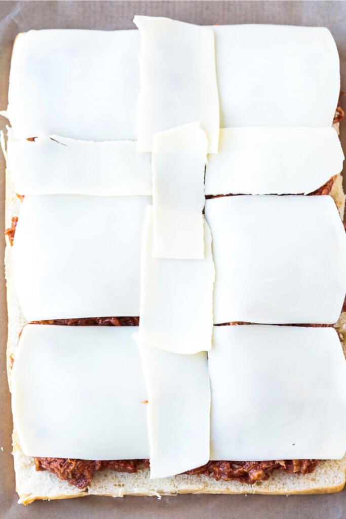 slices of mozzarella cheese on pulled pork with buns