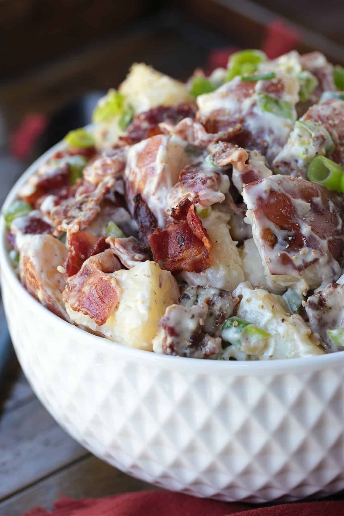 Ranch Potato Salad is a delicious, make ahead side dish! A hearty and tangy potato salad with creamy red potatoes and thick, crisp bacon. ranch potato salad in white bowl form the side