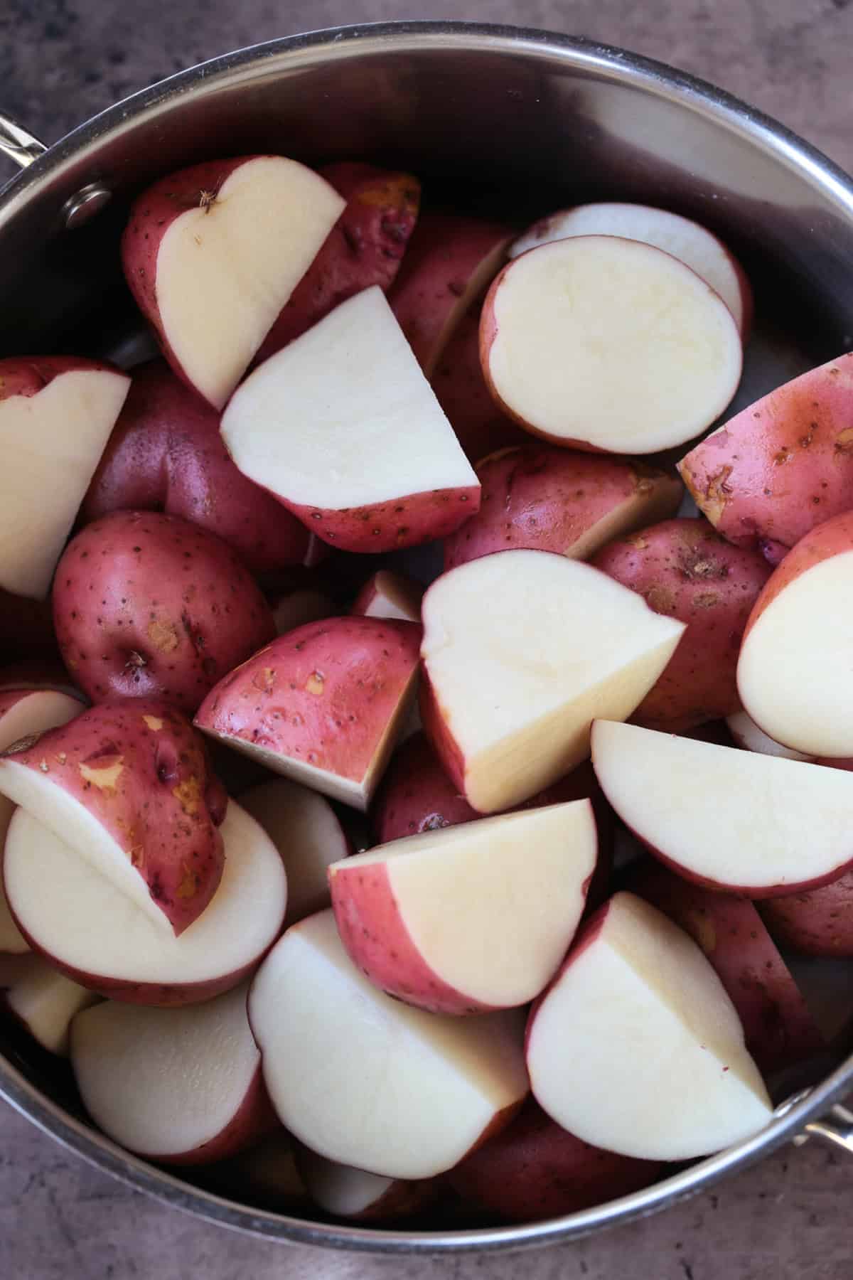 Ranch Potato Salad is a delicious, make ahead side dish! A hearty and tangy potato salad with creamy red potatoes and thick, crisp bacon. red potatoes cut in half in a pot