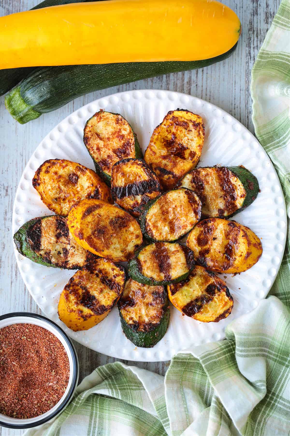 Grilled Zucchini and Squash is an easy side dish for any meal! Seasoned with our all purpose spice blend and grilled to perfection! slices of grilled zucchini and squash layered on white plate
