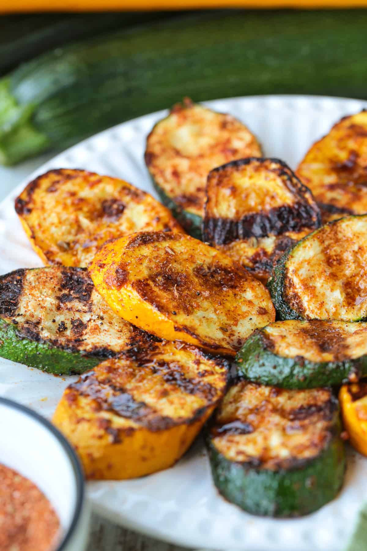 Grilled Zucchini and Squash is an easy side dish for any meal! Seasoned with our all purpose spice blend and grilled to perfection! grilled slices of zucchini and squash stacked on plate