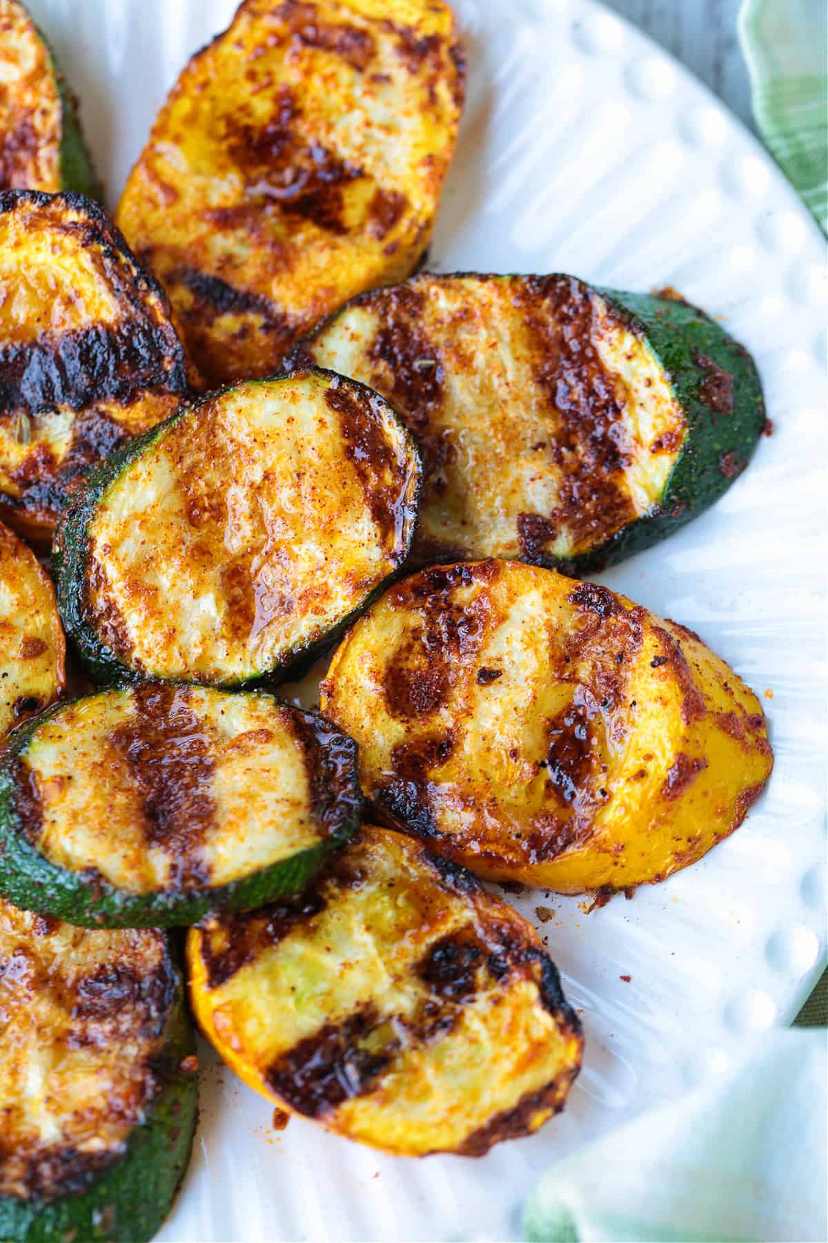 Grilled Zucchini and Squash is an easy side dish for any meal! Seasoned with our all purpose spice blend and grilled to perfection! grilled zucchini and squash layered on white plate
