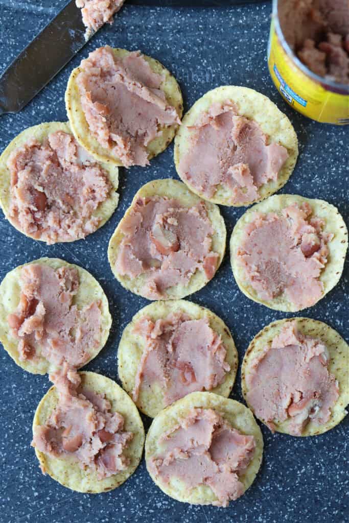 Air Fryer Nachos are so easy to make your kids can do it on their own. Ready in just 5 minutes for after school snacks, appetizers or dinner! refried beans on round tortilla chips