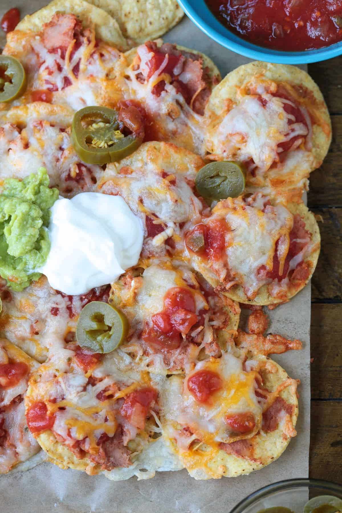 Air Fryer Nachos are so easy to make your kids can do it on their own. Ready in just 5 minutes for after school snacks, appetizers or dinner! nachos with toppings on parchment paper