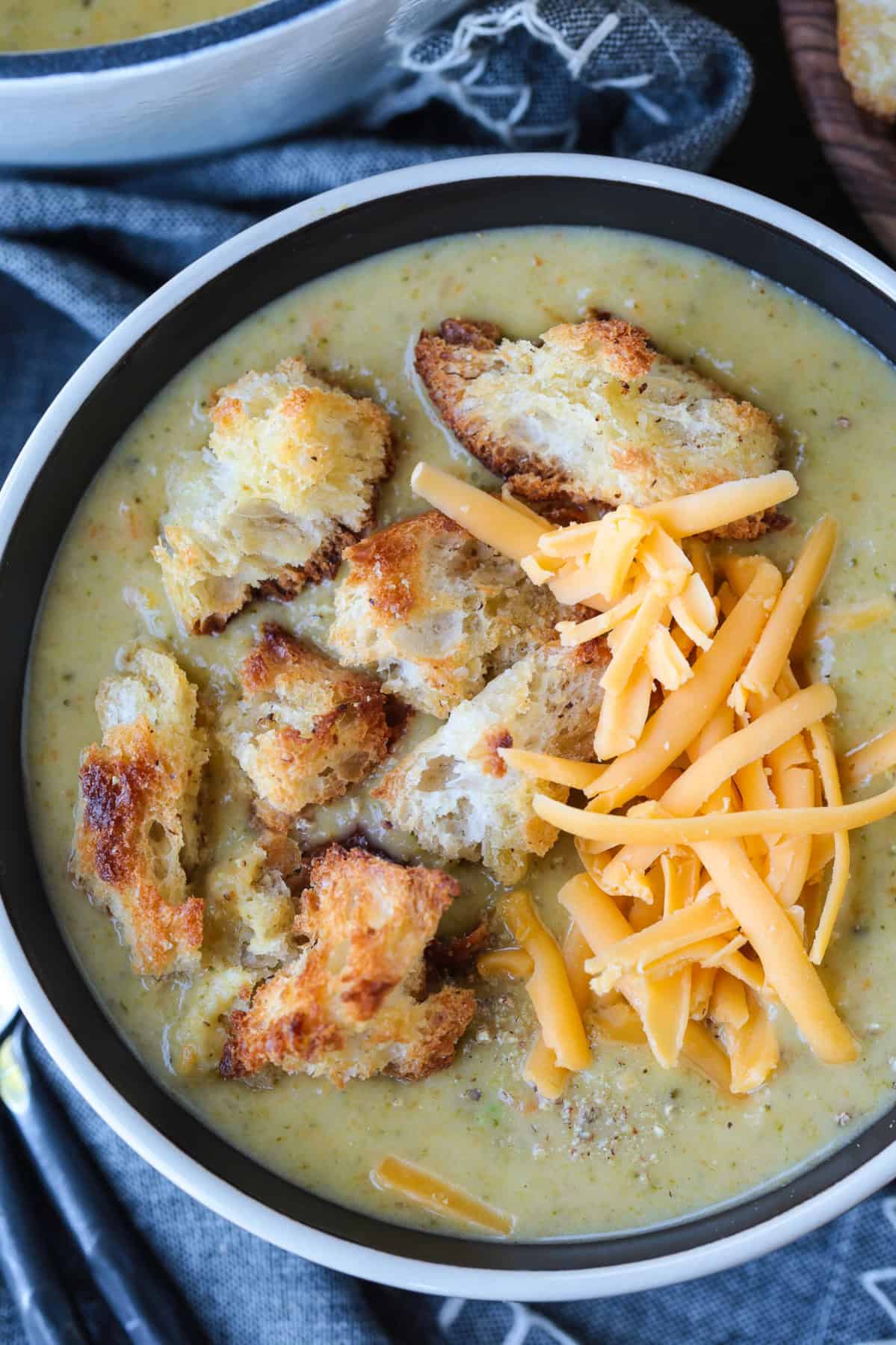 broccoli cheese soup in bowl with croutons and shredded cheese