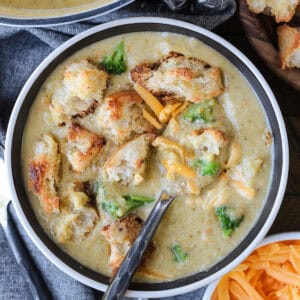 broccoli cheese soup in bowl with spoon and croutons